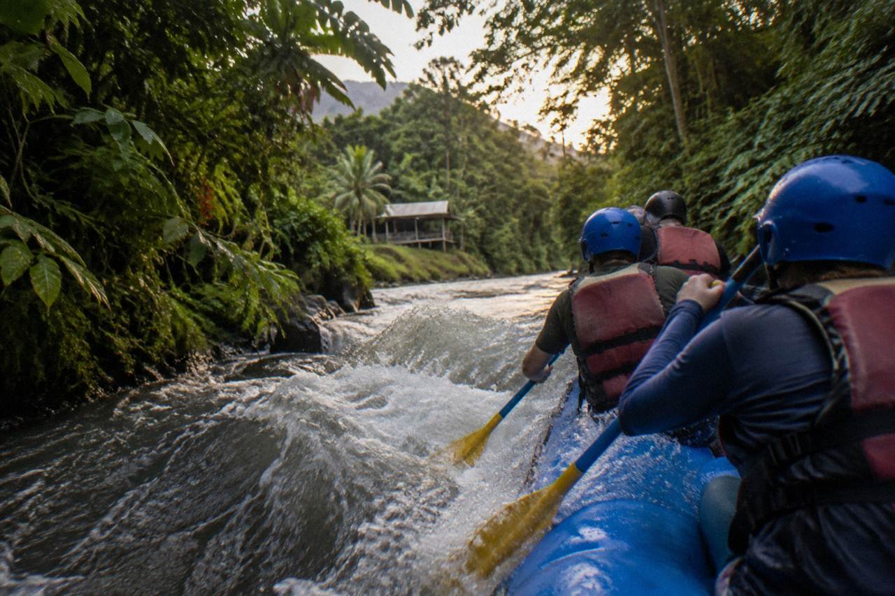 A raft cutting through a standing wave in a narrow jungle river channel