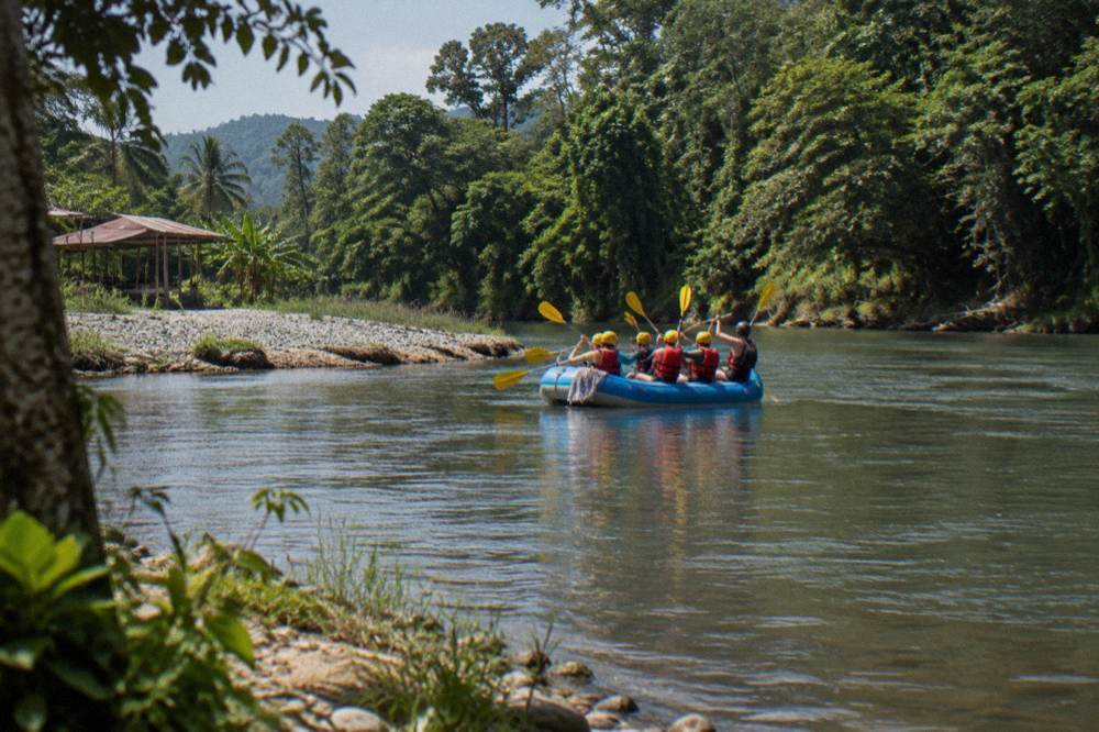 Family in helmets and life jackets celebrating in a raft on calm water