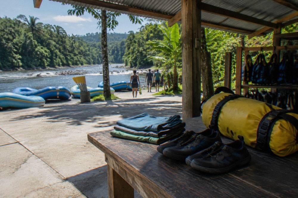 Folded quick-dry shirts, water shoes and a dry bag ready for a river trip