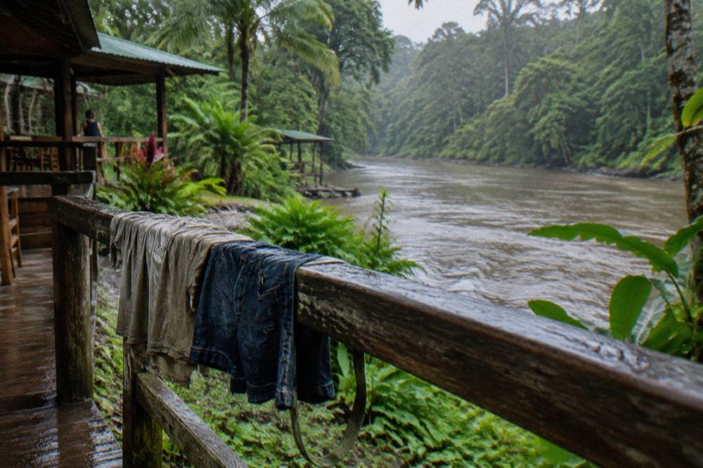 Wet cotton shirt and denim shorts hanging to dry on a railing beside a river