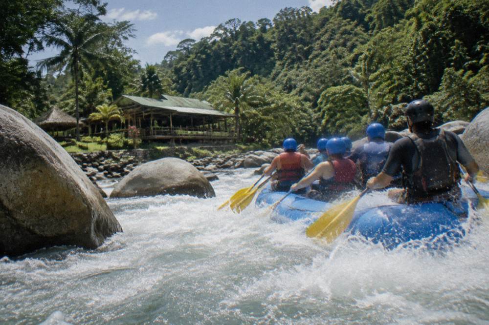 Paddlers in helmets and life jackets digging paddles into aerated whitewater