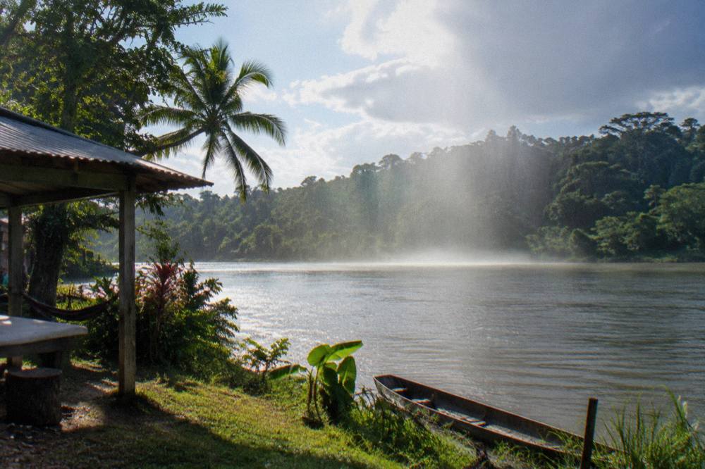 Afternoon rain shower falling over dense rainforest along a tropical river valley