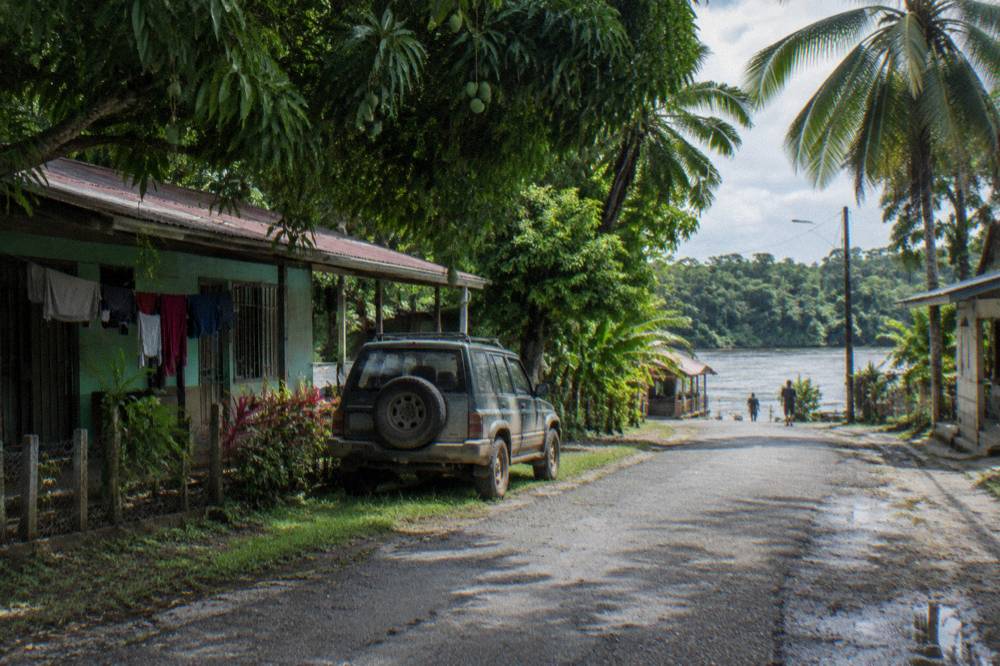 Quiet street in a small Costa Rican lowland town with green trees and colorful simple buildings