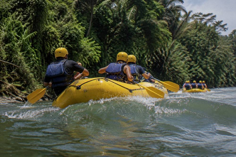 Raft with paddlers in helmets and life jackets on a jungle river