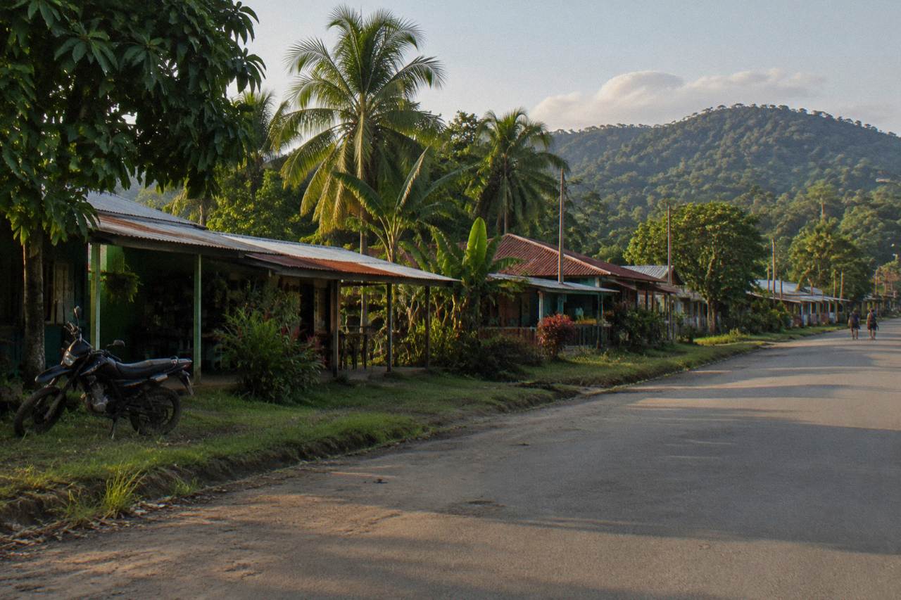 Quiet main street in a small river town with green hills behind tin roofs