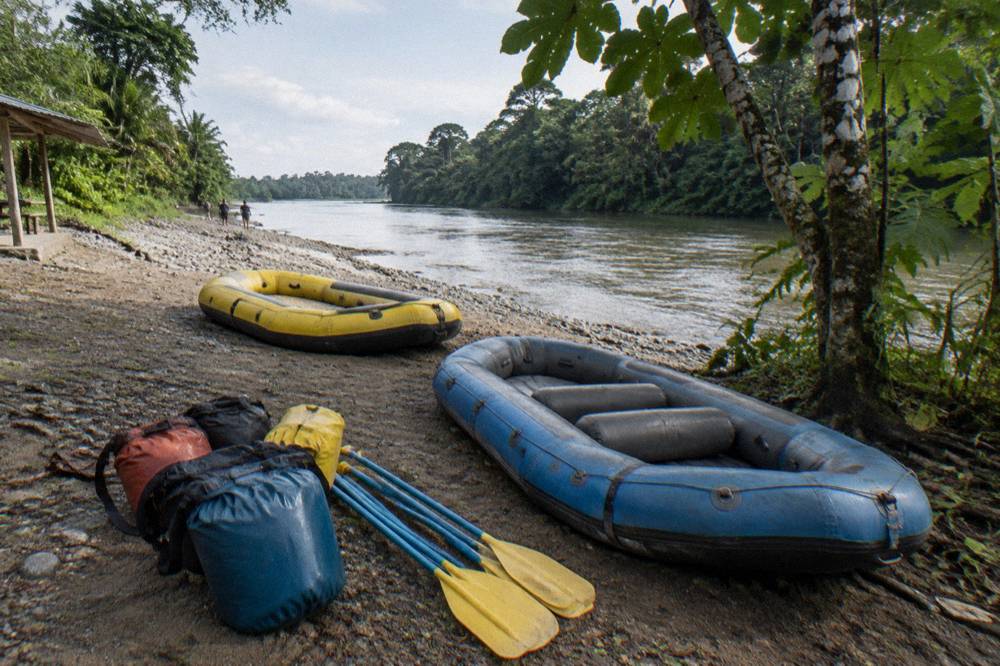 A rafts and gear laid out at a jungle riverbank launch area in the morning