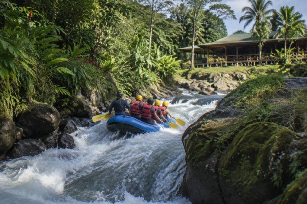 A raft dropping through a steep wave in a narrow jungle channel