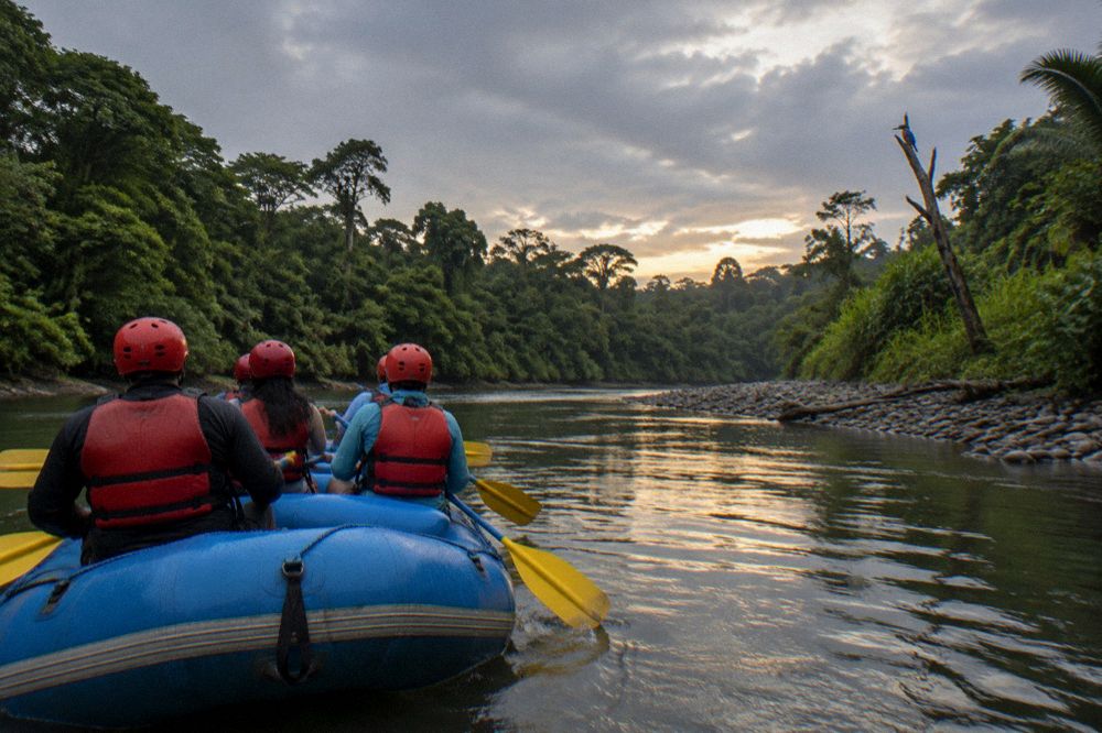 Smiling paddlers in helmets and life vests on a raft in calm river water