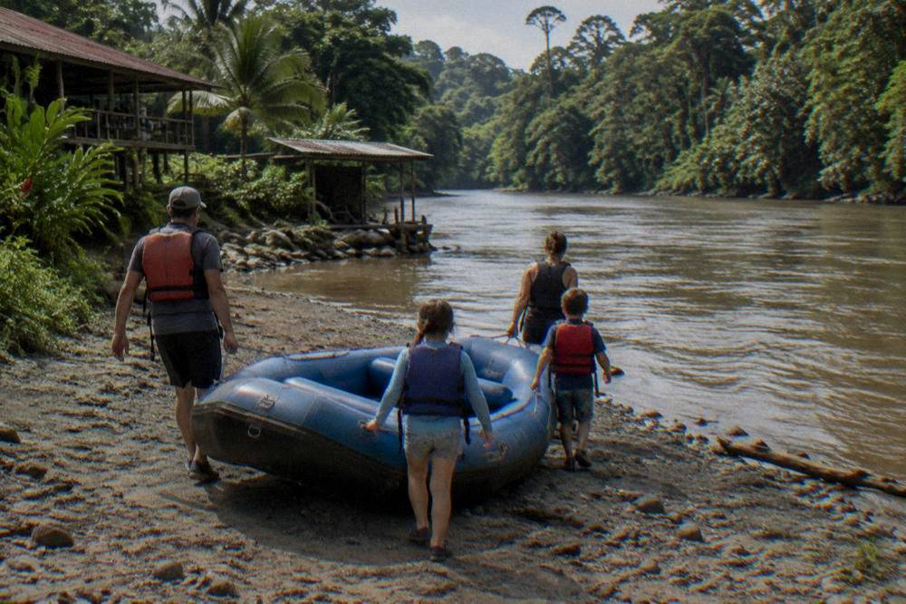 A family in life jackets carrying a raft toward the water
