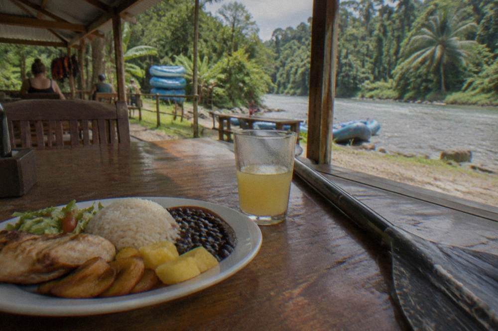 Spread of Costa Rican lunch dishes, rice, beans, plantains and fruit, on a table at a river outpost