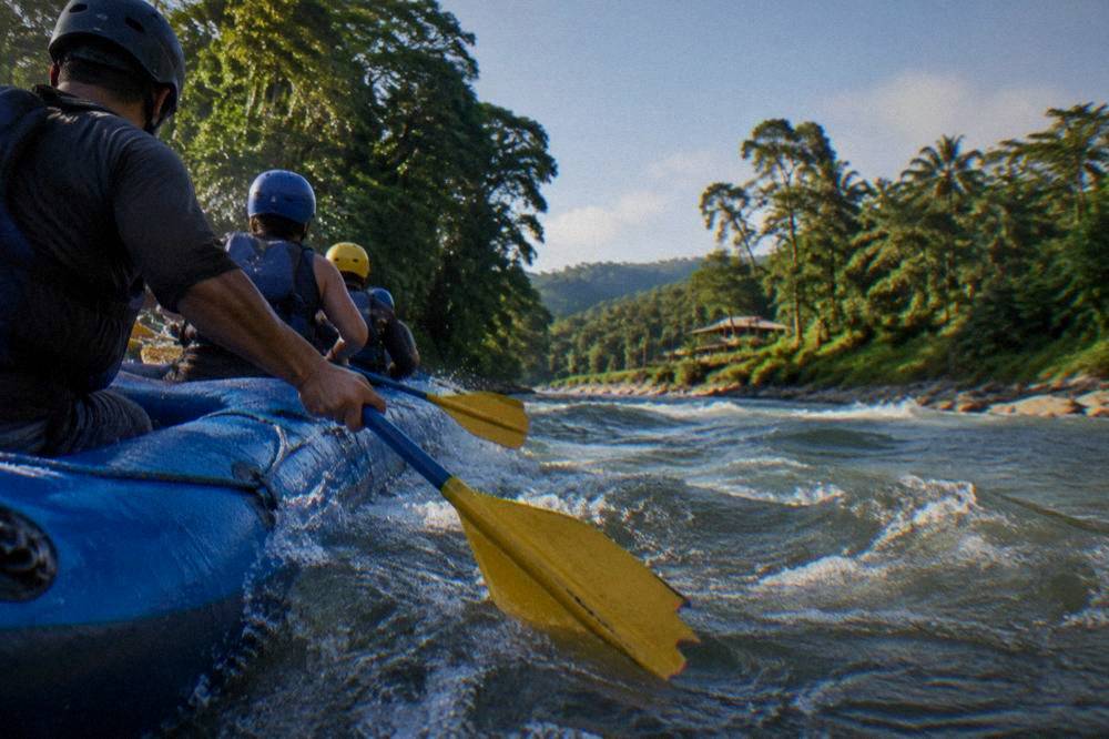 A guide raft paddling in formation through a rolling wave train in bright morning light