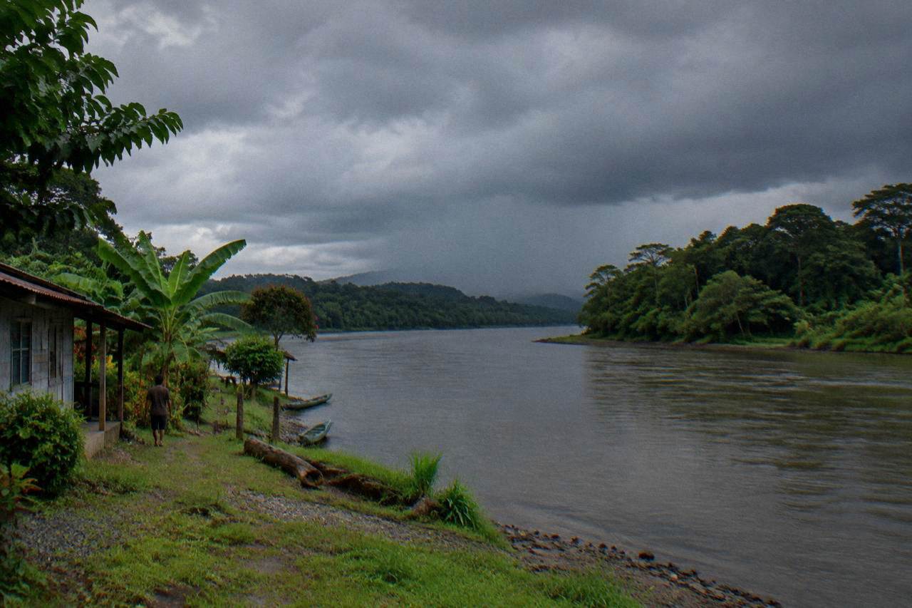 Low rainforest hills along the Sarapiqui River under heavy tropical clouds.