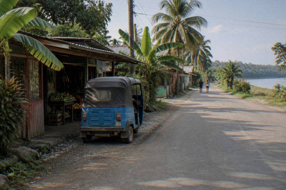 A small town street in a tropical lowland setting with green vegetation at the edges