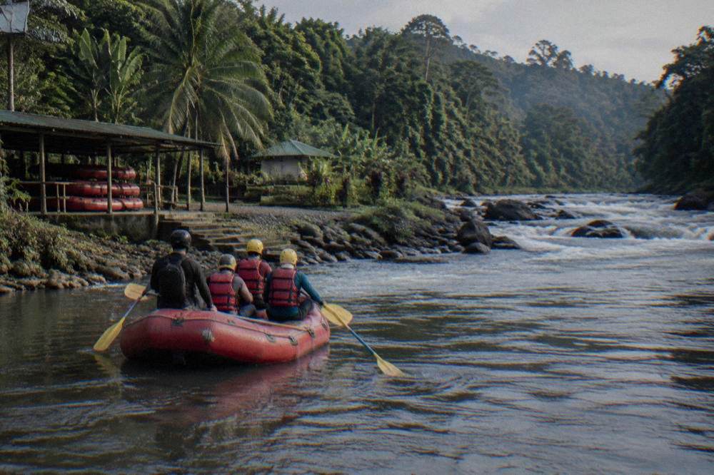 A raft with paddlers in helmets and life jackets on a jungle river